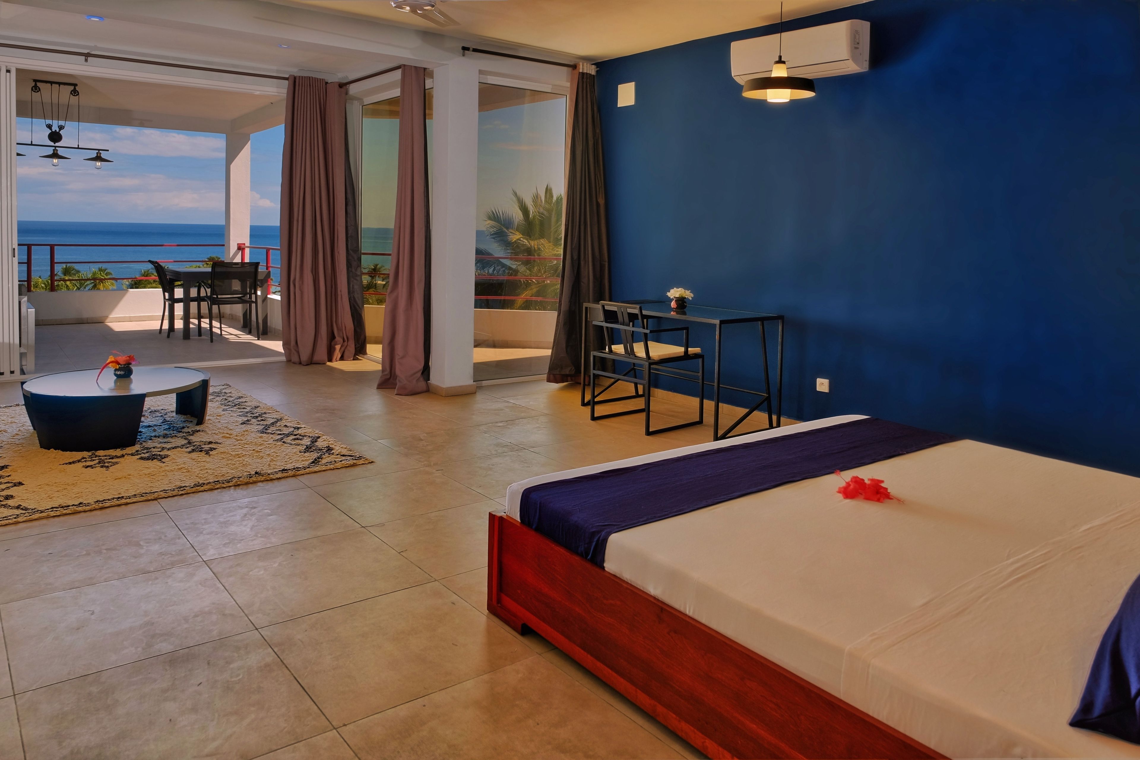 A hotel room with a bed, a desk, and a view of the ocean.