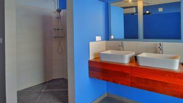 A modern bathroom with a walk-in shower, two sinks, and a large mirror.