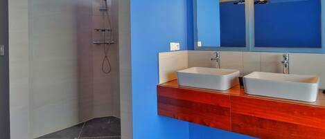 A modern bathroom with a walk-in shower, two sinks, and a large mirror.