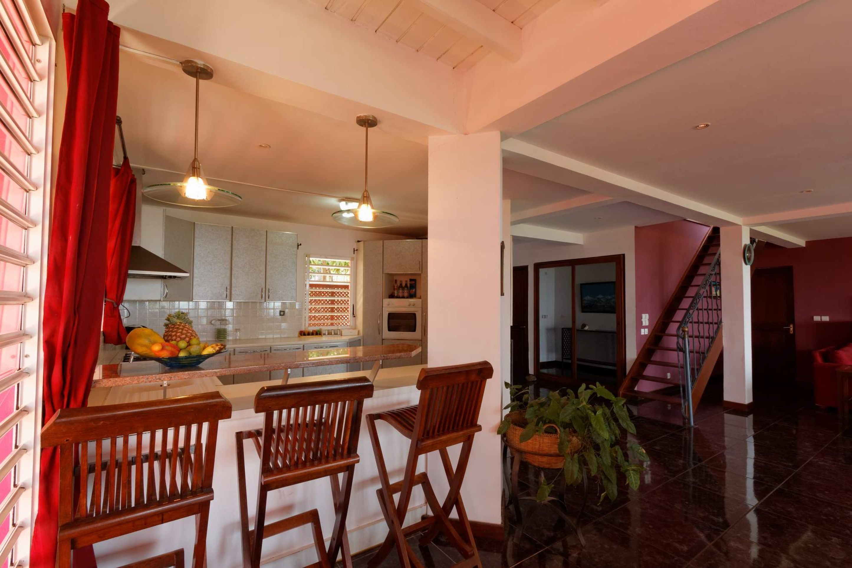 A modern kitchen with a central island, wooden chairs, and a fruit bowl.
