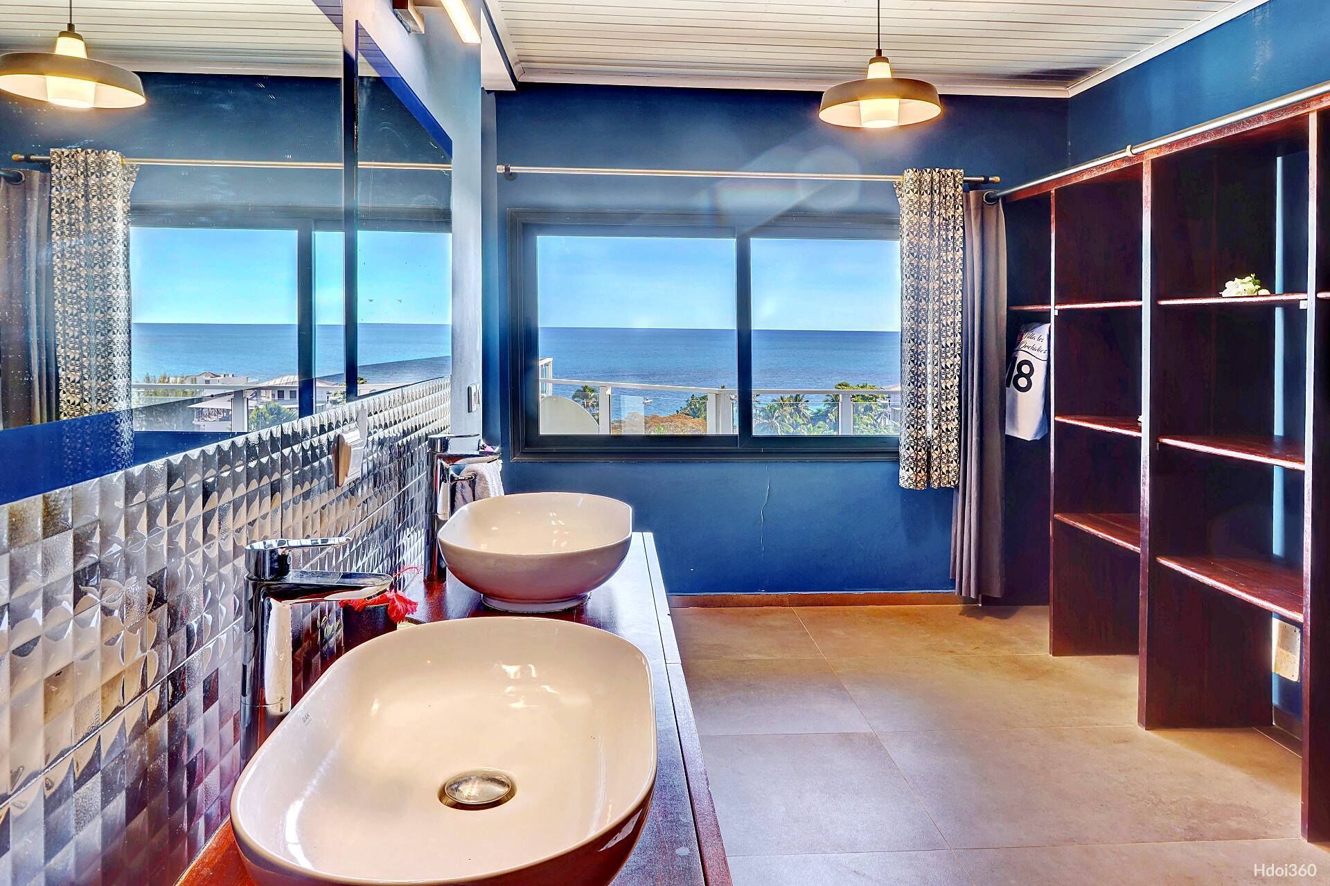 A bathroom with two sinks, a large mirror, and a view of the ocean.