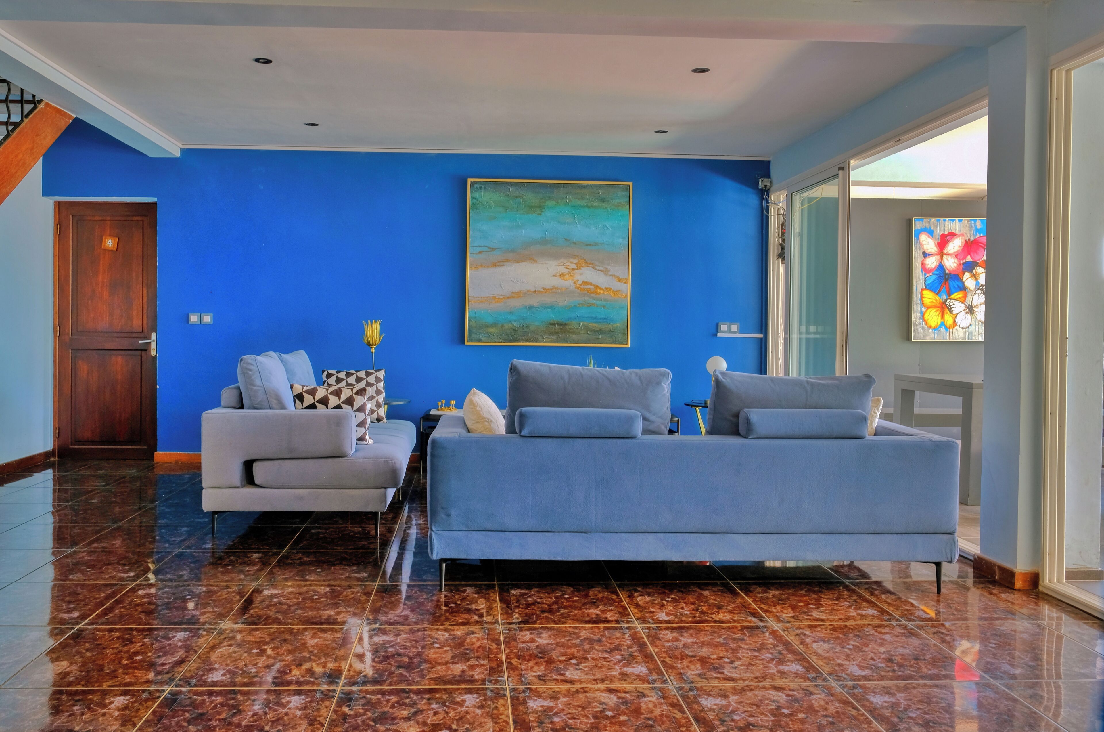 Una habitación con pared azul, un cuadro grande, un sofá y una cama.