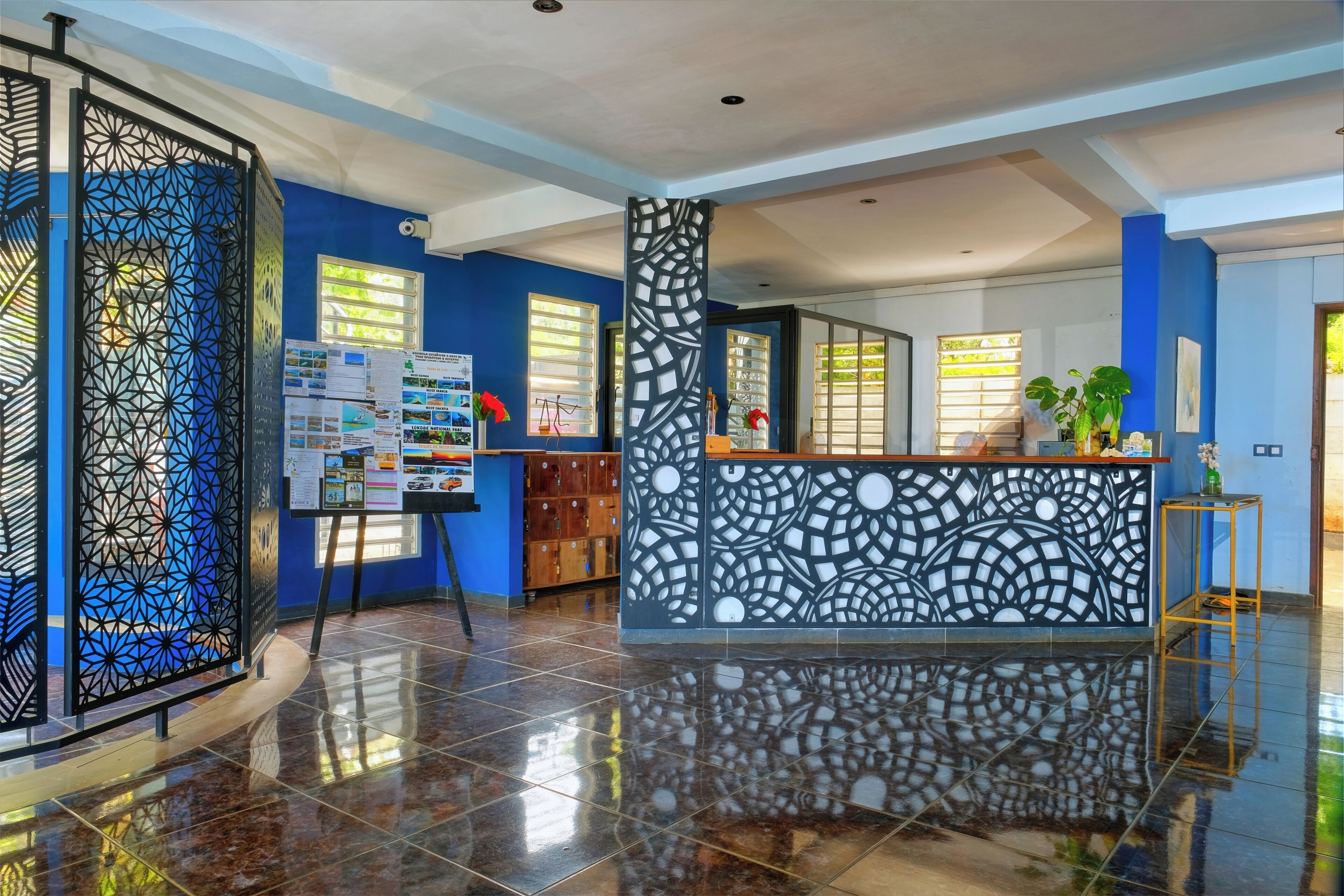 A hotel lobby with a reception desk, blue walls, and a decorative partition.