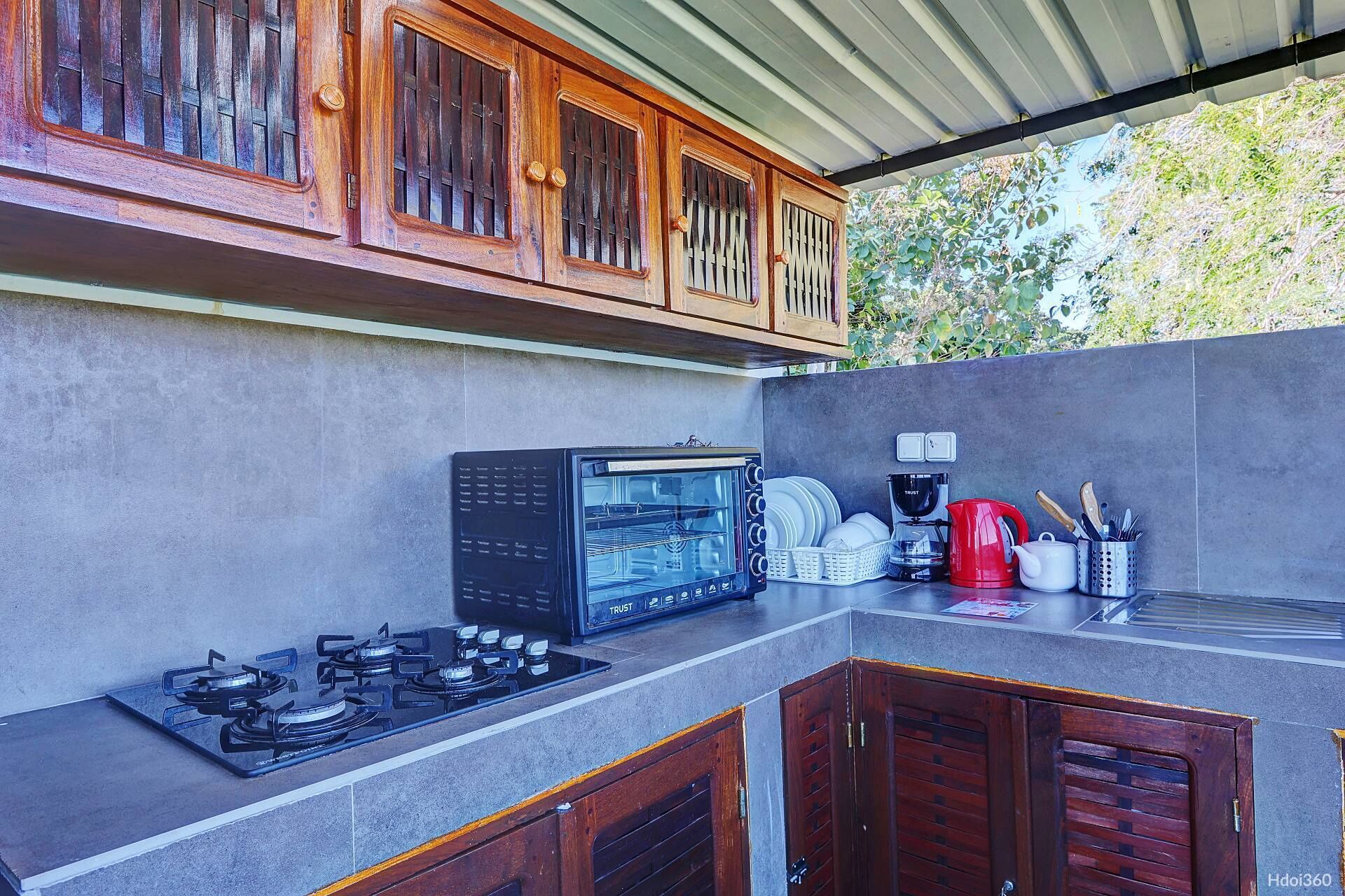 An outdoor kitchen with a gas stove, a built-in oven, and wooden cabinets.