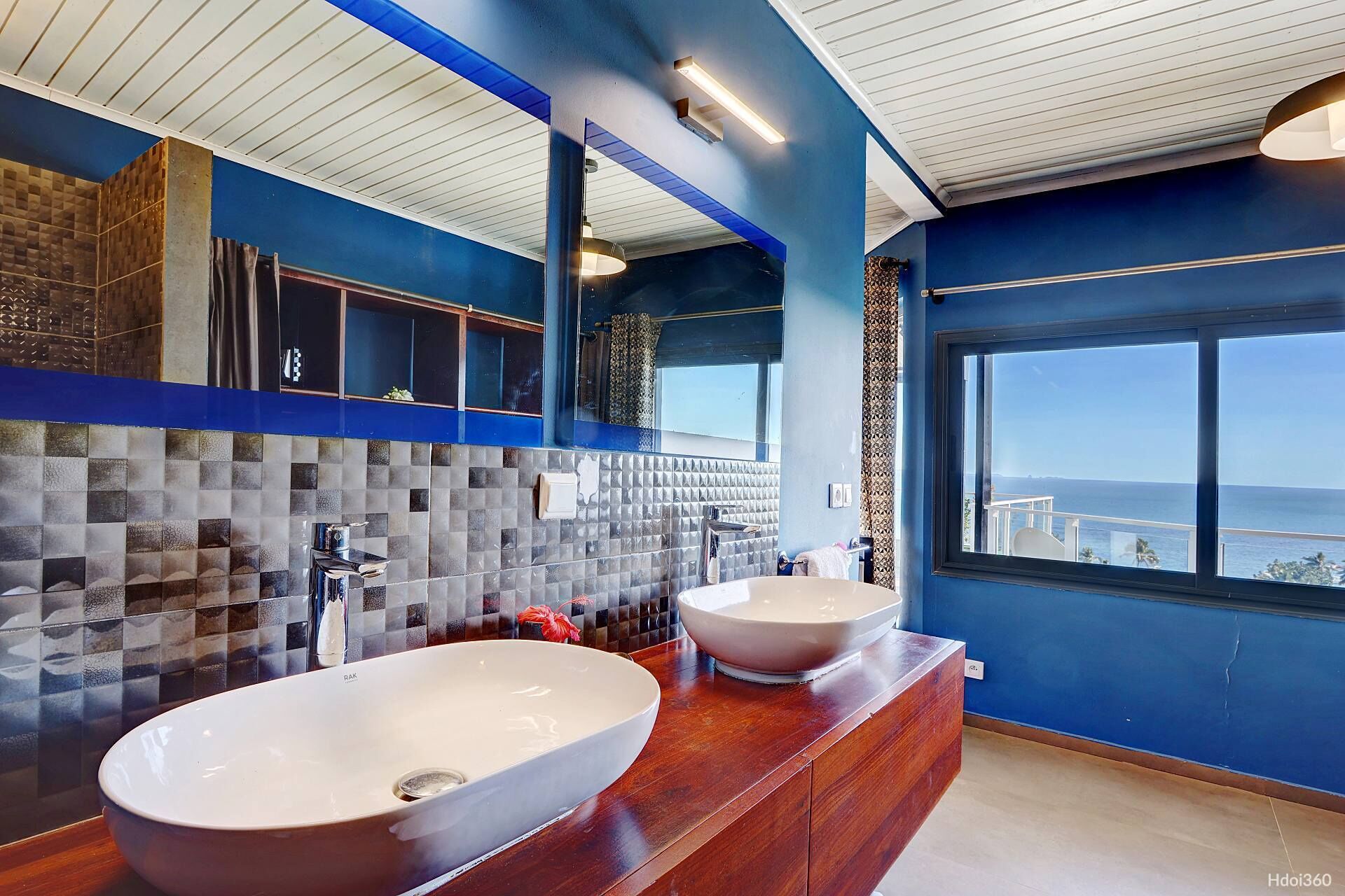 Een moderne badkamer met twee grote wastafels, een spiegel en uitzicht op de oceaan.