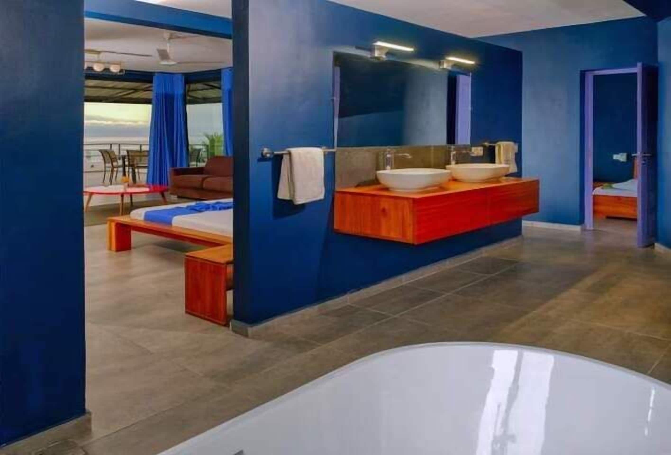 A modern bathroom with a large bathtub, a wooden vanity with a mirror, and a seating area with a sofa and a small table.