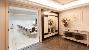A hotel lobby with a conference room, a reception desk, and a decorative mirror.