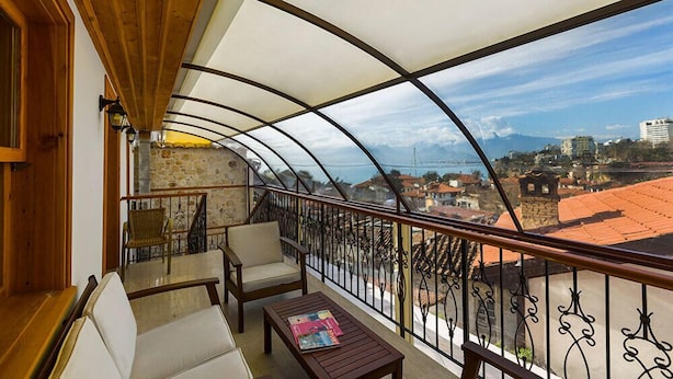 Uma varanda com vista para uma cidade costeira, mobiliada com um sofá, cadeiras e uma mesa.