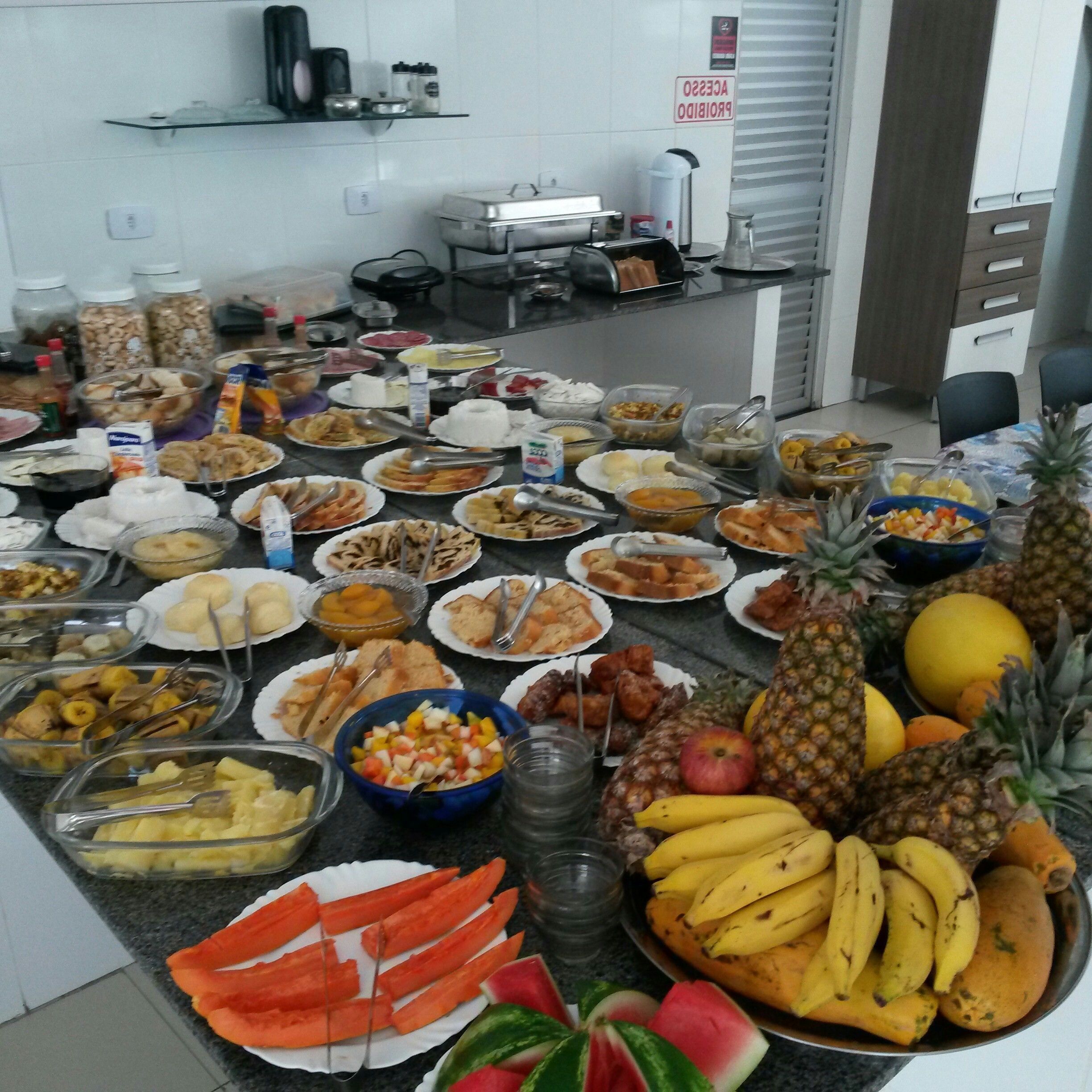 Mesa de buffet com diversos alimentos e uma exposição de frutas.