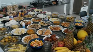 Mesa de buffet com diversos alimentos e uma exposição de frutas.