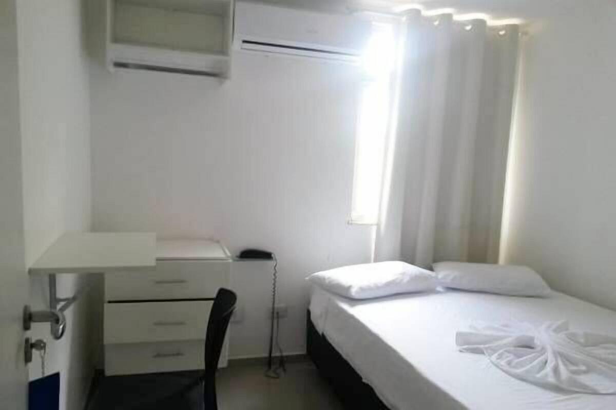 Une petite pièce propre, avec un lit, un bureau et une chaise.
