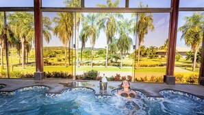 A hot tub with a view of a golf course and palm trees.