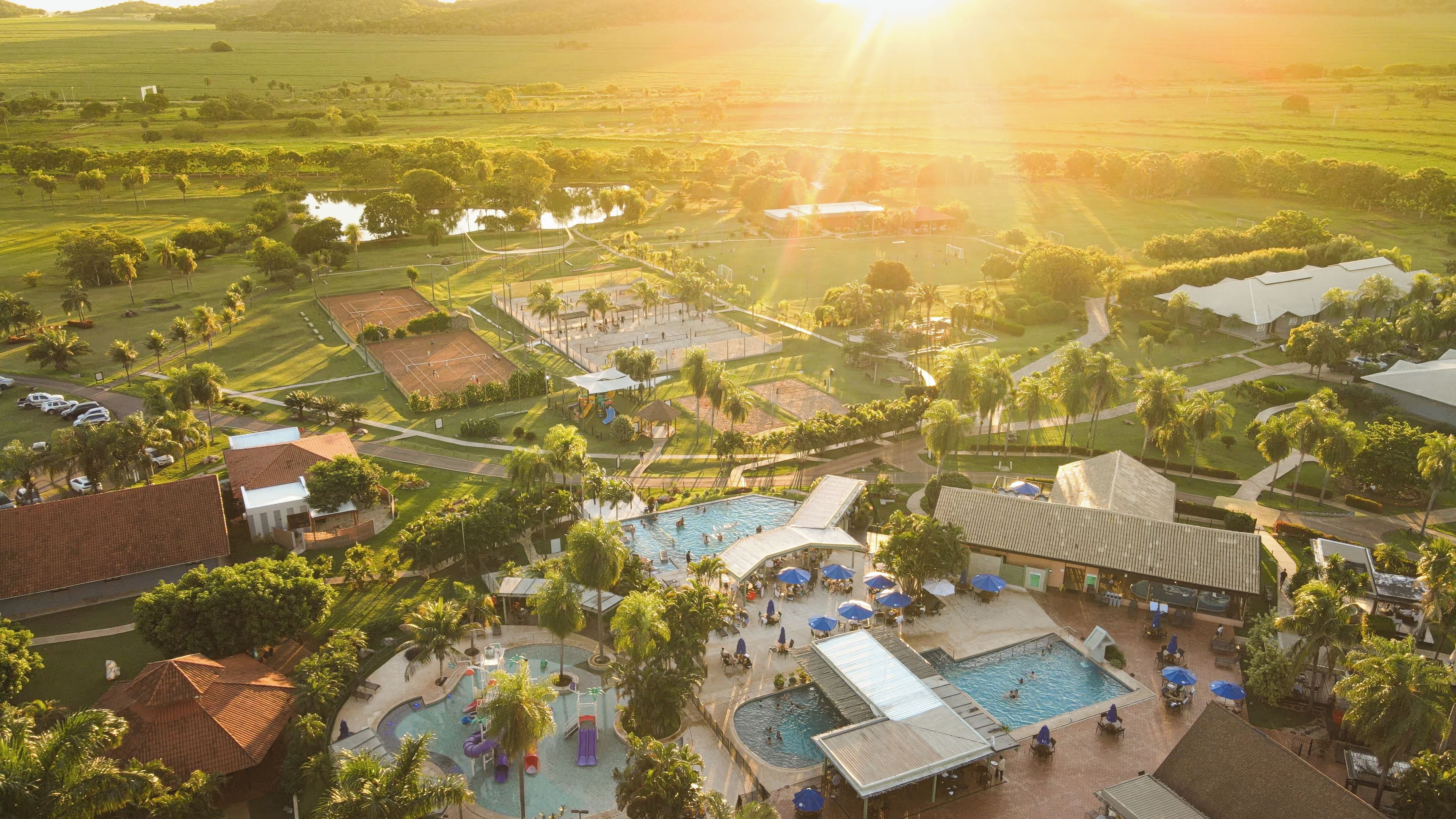 A resort with multiple swimming pools, tennis courts, and a large open field.