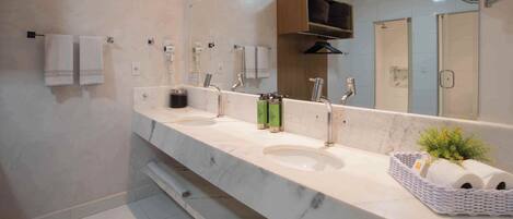 A modern bathroom with three sinks, a large mirror, and a towel rack.