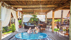 A wooden deck with a pool, outdoor seating, and a covered area with a sign.
