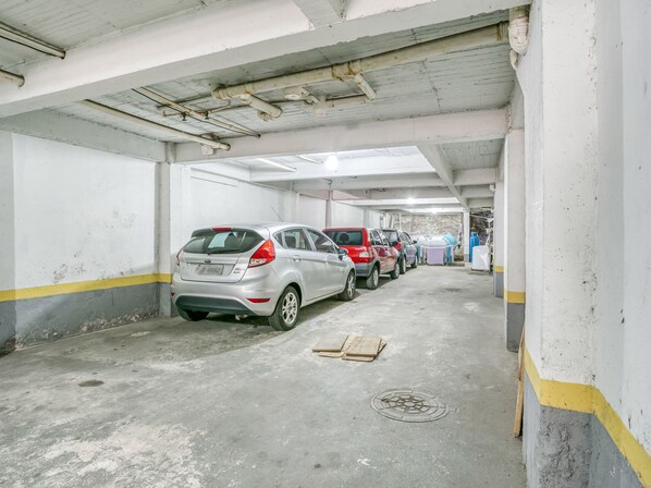 Eine Parkgarage mit Betonböden und weißen Wänden, mit mehreren parkenden Autos und einem blauen Wassertank im Hintergrund.