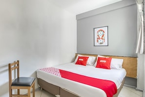 Une chambre d’hôtel avec un lit, une chaise et un tableau encadré au mur.