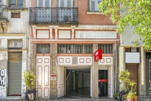 L’entrée de l’hôtel est dotée de deux portes, un balcon orné de balustrades décoratives et une enseigne indiquant le nom de l’hôtel.