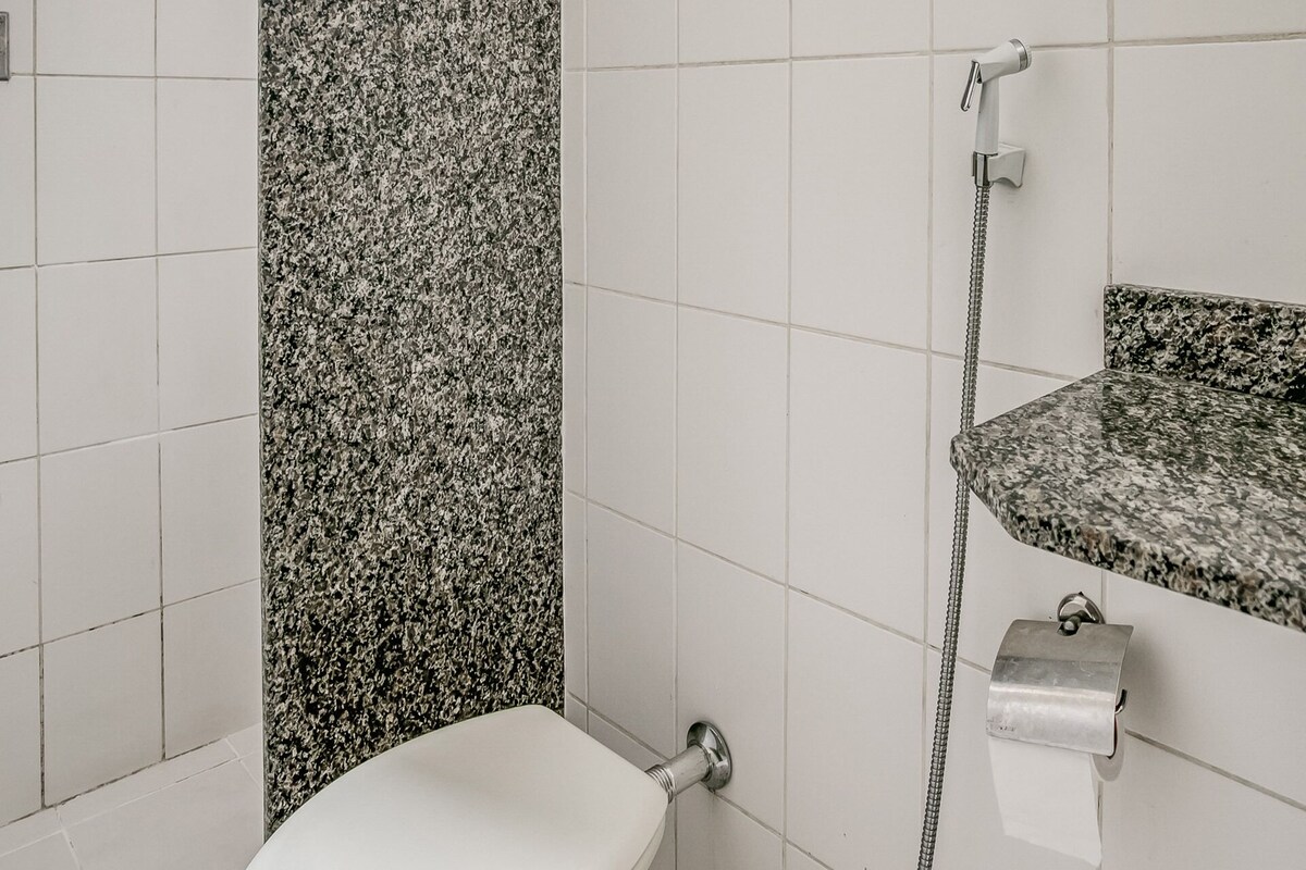 A bathroom with a toilet, a shower, and a sink with a granite countertop.