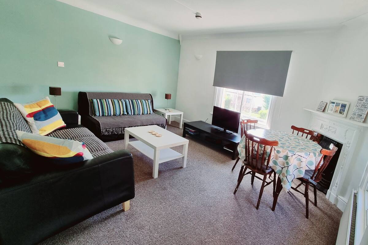 A living room with a sofa, coffee table, TV, and dining table.