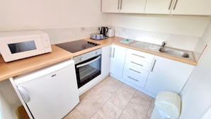 A compact kitchen with a microwave, stove, oven, sink, and cabinets.
