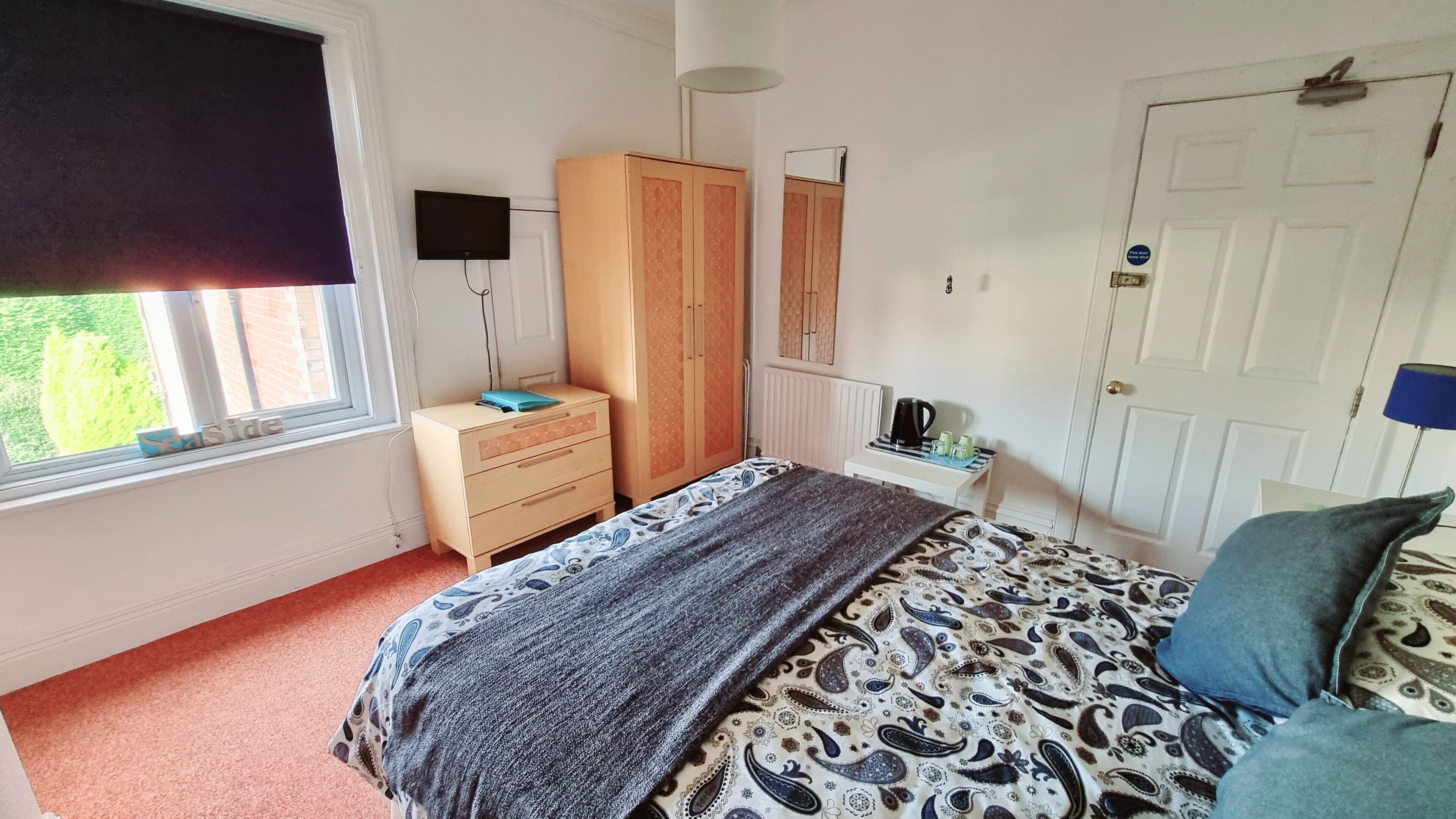 A bedroom with a bed, dresser, wardrobe, and a television.