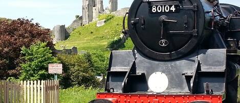 A steam locomotive with the number 80104 at a station, with a historic building in the background.