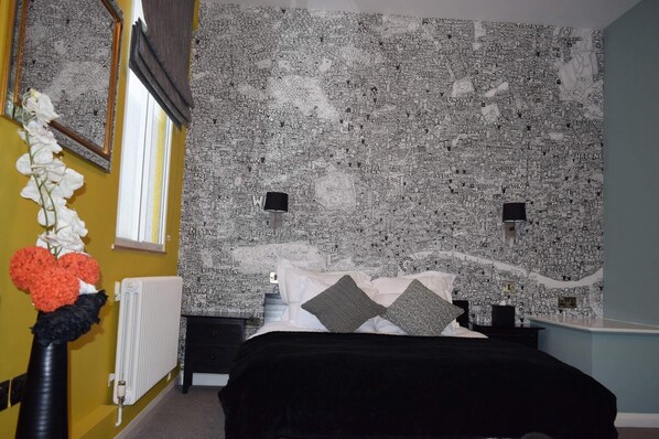 Un dormitorio con una cama, un radiador, una ventana y una pared decorada con un mapa.