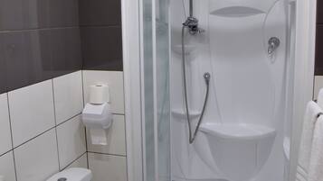 Moderni kylpyhuone, jossa on lasiseinällä varustettu suihku, wc ja pesuallas.