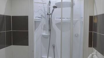 Un baño moderno con ducha acristalada, inodoro y lavamanos.