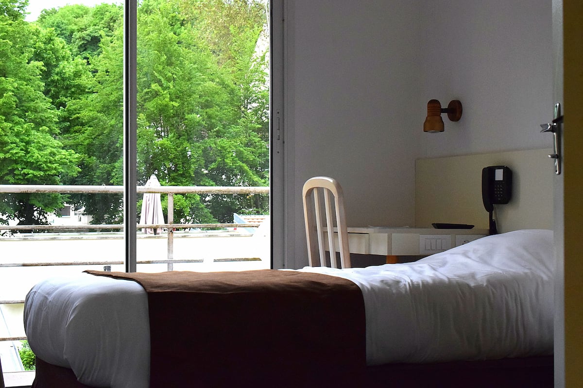 Una habitación de hotel con una cama, una silla, un escritorio y un teléfono.