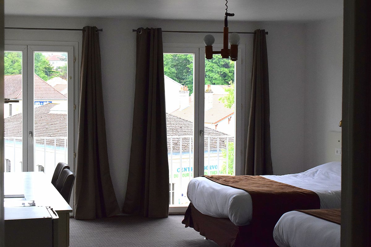 Una habitación de hotel con una cama, un escritorio y vistas a través de un ventanal grande.