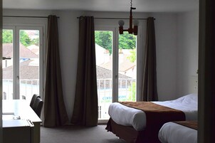 Una habitación de hotel con una cama, un escritorio y vistas a través de un ventanal grande.