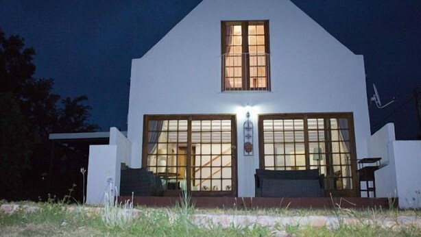 A white building with large windows and a central door, illuminated by exterior lighting. - Sweetie Pie Clarens Self Catering Cottages (Clarens)
