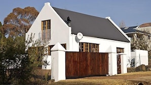 A white building with a dark roof, a wooden fence, and a satellite dish. - Sweetie Pie Clarens Self Catering Cottages (Clarens)