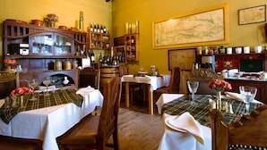 Een restaurantinterieur met houten meubels, witte tafellaken en een grote kaart aan de wand.