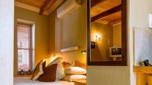 Een slaapkamer met een bed, een houten hoofdbord, een spiegel en een raam.