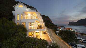 Situated on a hillside, this two-story residence offers a view of the coastline from its upper balcony.