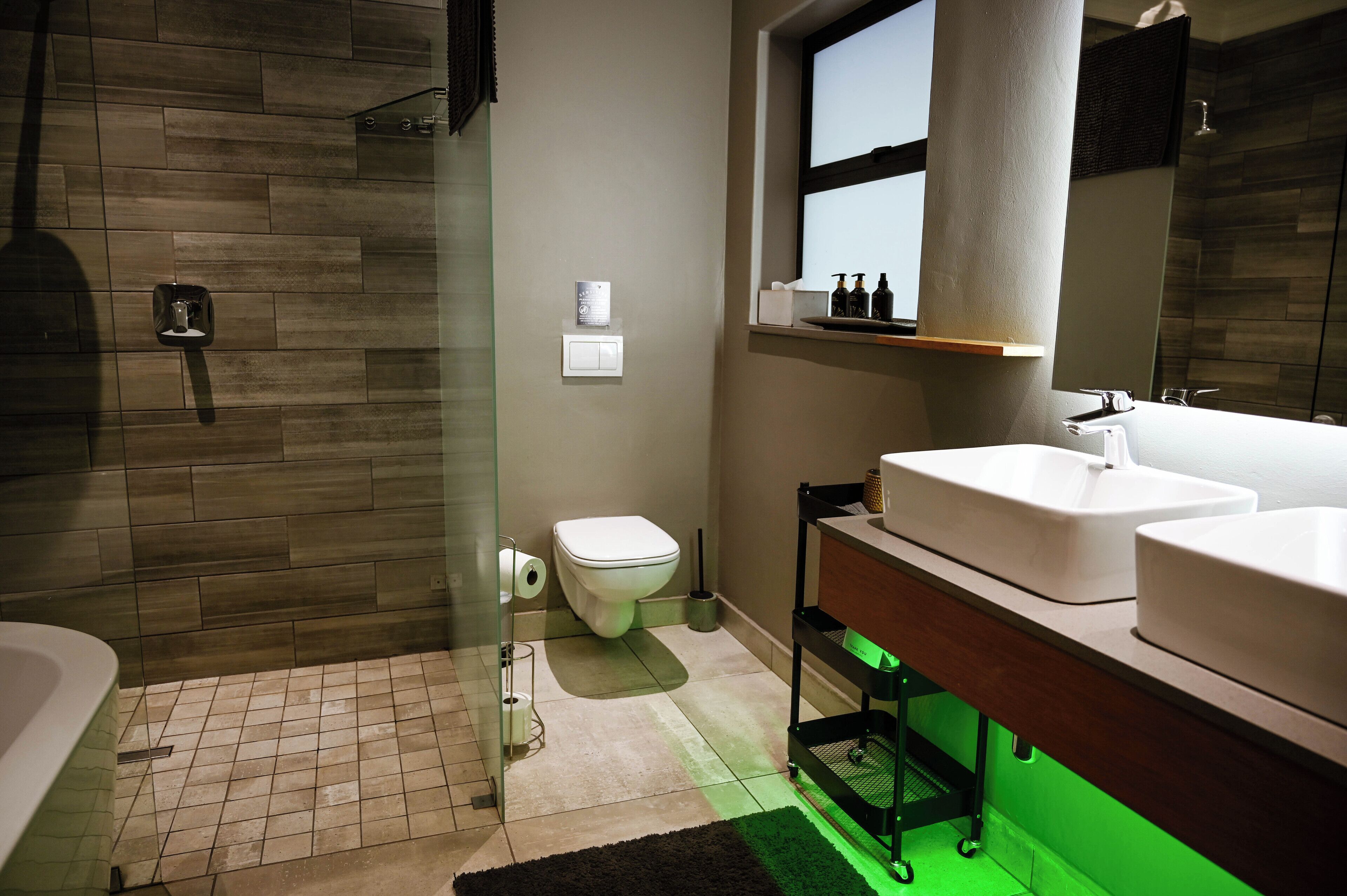 Un baño moderno con ducha, inodoro e lavamanos dobles.