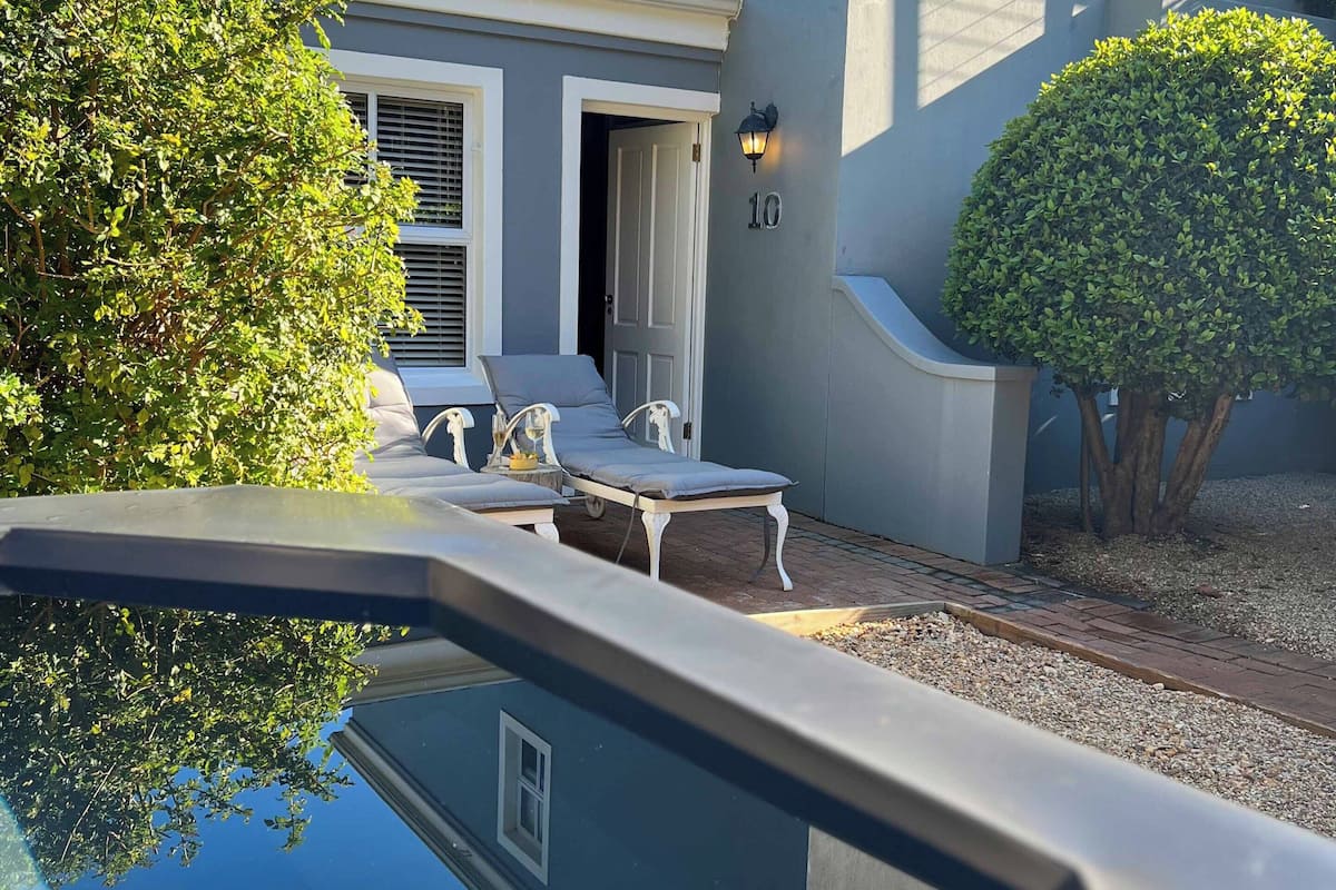Una casa con piscina, mobiliario de exterior y un jardín bien cuidado.