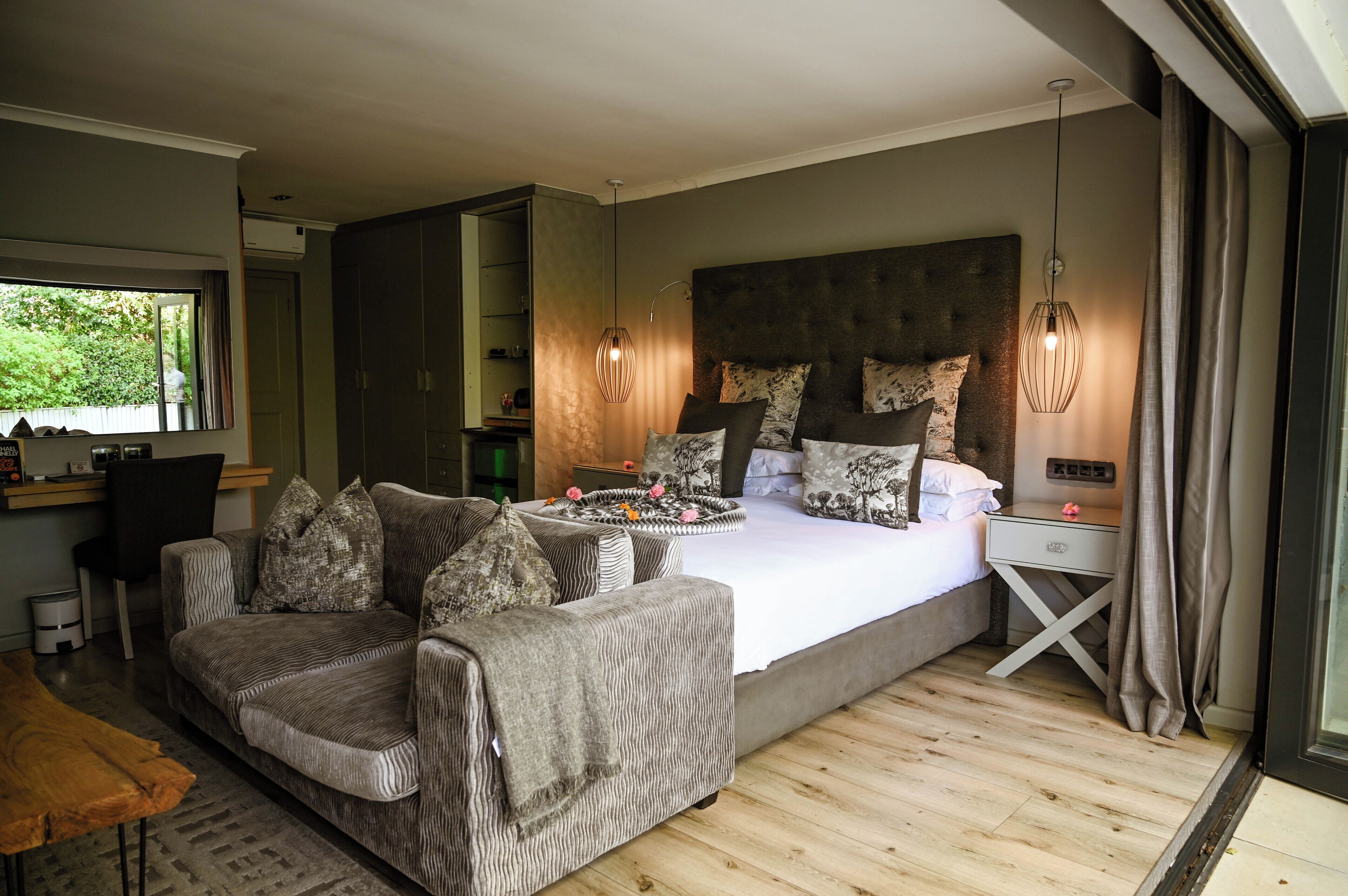 Een slaapkamer met een groot bed, een bank, een nachtkastje en een bureau.
