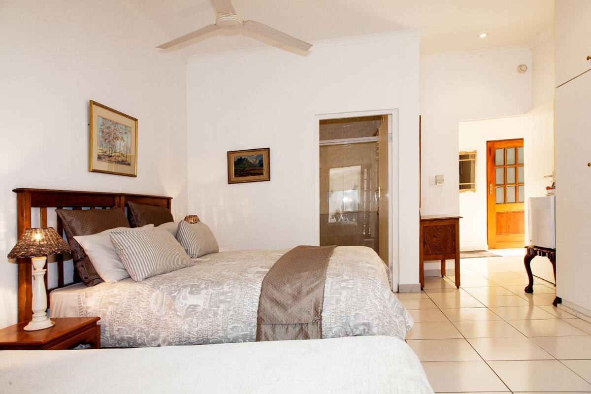 A bedroom with a bed, bedside table, lamp, and a ceiling fan.