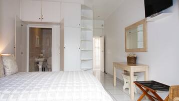 A bedroom with a bed, a desk, a chair, a TV, and a wardrobe.