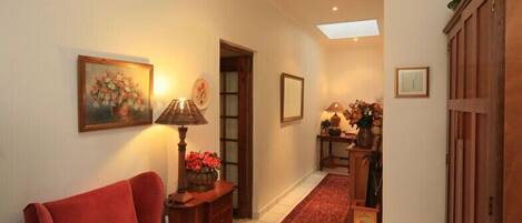 A hallway with a red sofa, a lamp, a painting, and a wooden cabinet.
