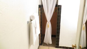 A bathroom with a white towel hanging on a rack, a roll of toilet paper, and a curtain tied in the middle. - El Trovatore Motel (Kingman)