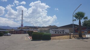 A parking lot with a sign for Route 66, a vintage car, and a mountain backdrop. - El Trovatore Motel (Kingman)