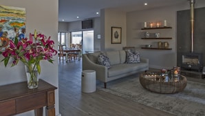A modern living room with a sofa, coffee table, and a vase of flowers. - Ocean Bay Guest House (Gqeberha (Port Elizabeth))