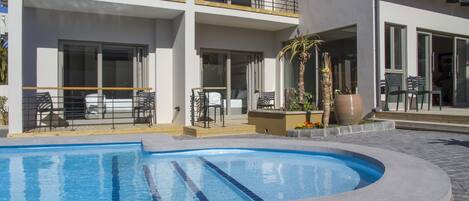 Un edificio moderno con piscina, mobiliario exterior y balcón.
