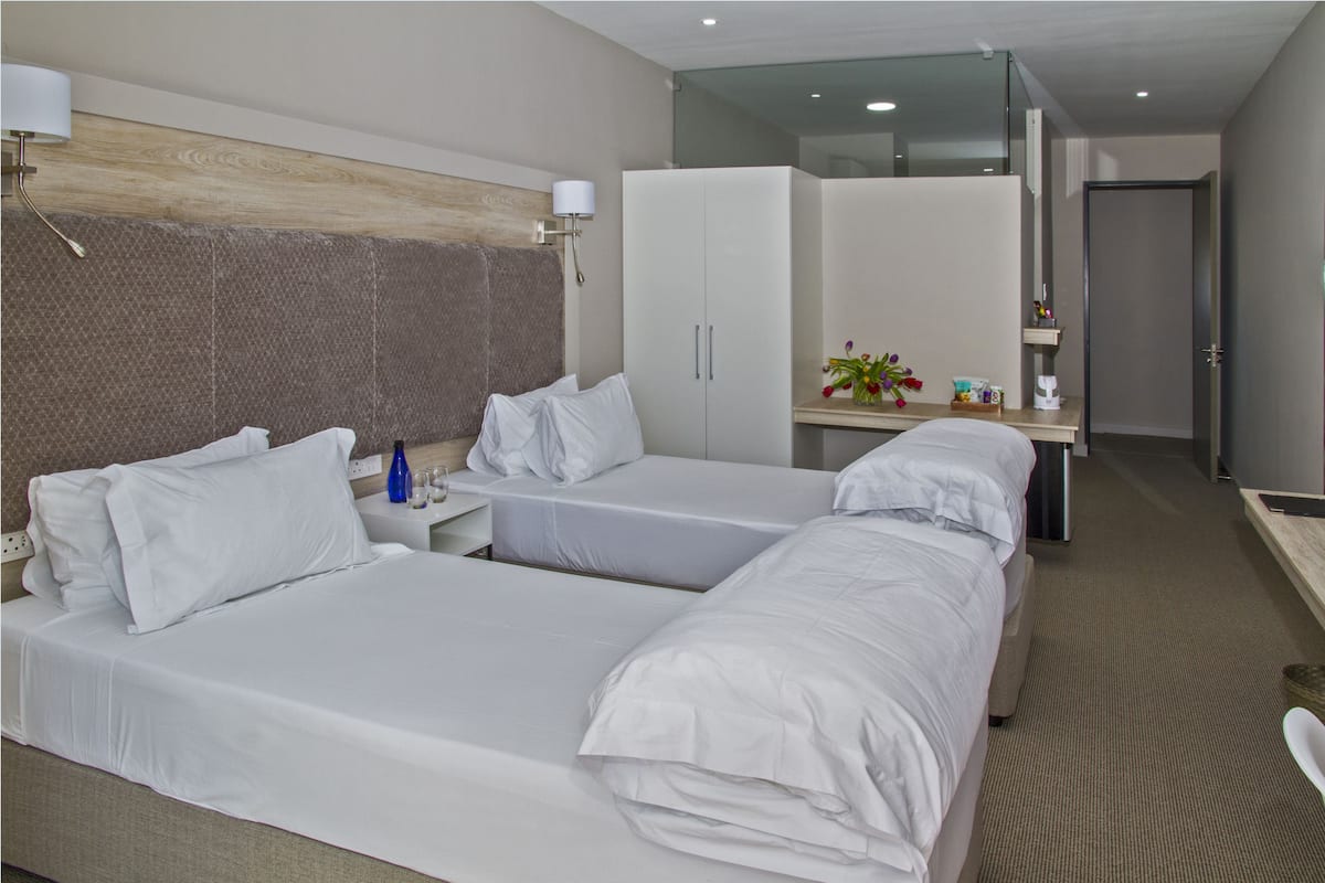 A hotel room with two beds, a desk, a wardrobe, and a bathroom.