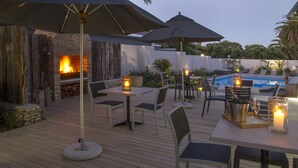 An outdoor patio with a pool, seating, and a fire feature. - Ocean Bay Guest House (Gqeberha (Port Elizabeth))